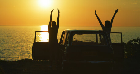 Wall Mural - Couple, silhouette and sunset at beach for road trip, freedom and excited for journey in nature. People, friends and shadow at car for travel, adventure and outdoor for memories at California ocean