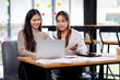 © David - Two asian confident business people point to graphs and charts to analyze market data, balance sheet, account, net profit to plan new sales strategies to increase production capacity.