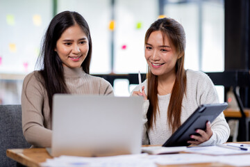 Two asian confident business people point to graphs and charts to analyze market data, balance sheet, account, net profit to plan new sales strategies to increase production capacity.	
