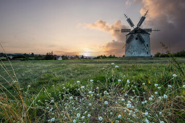 Windmill with wooden wings in a landscape setting. Fields, meadows and flowers appear in the sunset. Landscape shot in nature with a mill. historically untypical for the Balaton region in Hungary