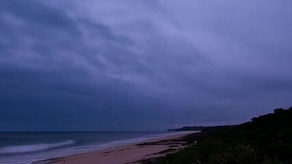 Aufkleber - The tranquil shoreline is adorned with soft waves lapping at the sandy beach under a twilight sky, while lush greenery frames the scene.