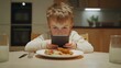 © HPMP Studio - child who is bored is eating at the table and looking at his mobile or tablet device