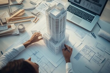 Poster - A designer working on architectural plans with a model of a skyscraper.