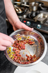 Wall Mural - Close-up of a chef’s hands holding a stainless steel bowl with mixed colorful ingredients in a professional kitchen setting. Ideal for culinary themes, food preparation