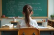 © Sergey - schoolgirl sits at a Desk at school on September 1.Holiday of knowledge. The child goes to school for the first time. Back to school. Concept of school education. Rear view.