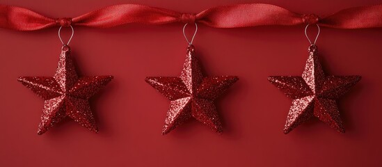 Poster - Glittery red star ornaments hanging from a red ribbon on a vibrant red background for festive tree decorations