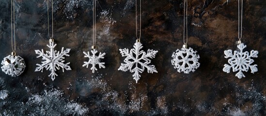 Poster - Elegant snowflake Christmas ornaments suspended against a textured dark winter backdrop creating a festive holiday atmosphere