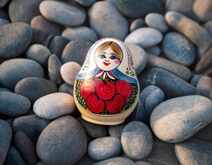 Wall Mural - A traditional Russian nesting doll decorated with red roses sits atop a bed of smooth grey river rocks.