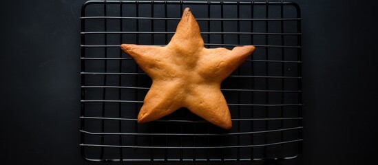 Aufkleber - Overhead view of a uniquely shaped star biscuit cooling on a black wire rack showcasing baking imperfections and rustic charm