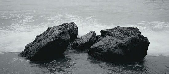 Poster - Monochrome seascape featuring textured rocks and gentle ocean waves creating a serene coastal atmosphere.