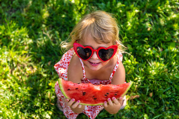 Poster - Child eating watermelon in the garden. Selective focus.