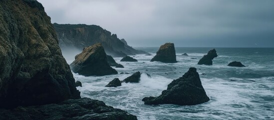Poster - Dramatic rocky coastline with turbulent waves under moody overcast sky ideal for nature and landscape photography themes