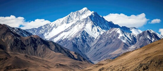 Poster - Majestic snow-capped mountain range under clear blue skies with rugged terrain showcasing nature's grandeur and beauty.