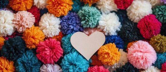 Leinwandbilder - Vibrant colorful pom poms scattered with a blank paper heart creating a cheerful and playful background for creative projects