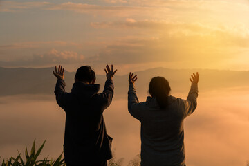 Wall Mural - Serene embrace of nature, Christian man and woman worship Jesus Christ with hands raised in prayer, silhouetted against sunrise. worship, christian, morning, man, woman, jesus christ, sunrise.