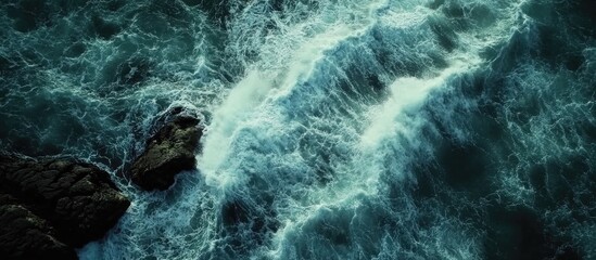 Poster - Aerial view of crashing ocean waves against rocky shore creating dynamic coastal landscape patterns
