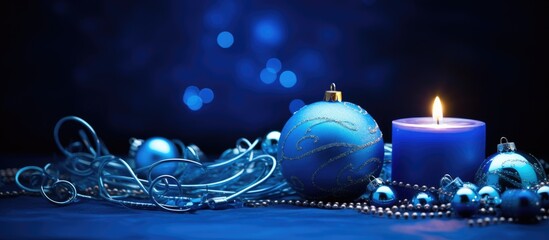 Poster - Decorative blue Christmas ornaments and a lit candle adorned with shimmering tinsel on a dark festive background