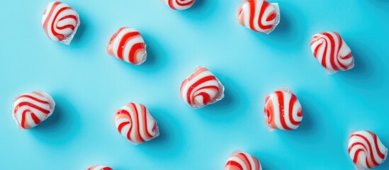 Poster - Striped Christmas candy on a blue background with red and white caramels in a flat lay arrangement perfect for festive themes