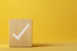 © Supawi - correct sign tick check mark on wooden block with copy space for the checklist on yellow background
