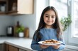 © Olena - Smiling young girl holding plate of cookies
