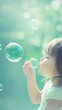 © fourtakig - Young Child Blowing Bubbles in a Pastel Green Background