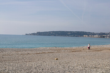 Wall Mural - Woman walking in the Fossan beach along the Mediterranean sea, in Menton, France.