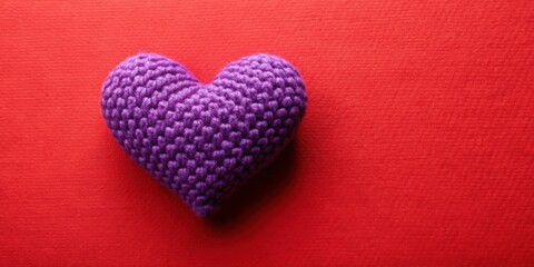 Poster - A single purple crocheted heart, lovingly crafted, rests on a vibrant red background, a symbol of warmth and affection.