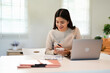 © Fahng - Asian Businesswoman Using laptop computer and working at office with calculator document on desk, doing planning analyzing the financial report, business plan investment, finance analysis concept.