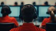 © pattaphorn - A group of individuals in red shirts, wearing headphones, focused on computer screens in a workspace setting.