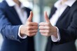 © Tascha - Two business professionals in suits giving synchronized thumbs-up – Focus on teamwork and success