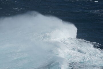 Wall Mural - majestic ocean waves crashing against shore, creating misty spray. deep blue water contrasts beautif