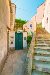 Wall Mural - The photo captures a view of Positano, with its colorful, stacked houses cascading down the cliffs, narrow winding streets, and vibrant coastline set against the clear blue sea and sky