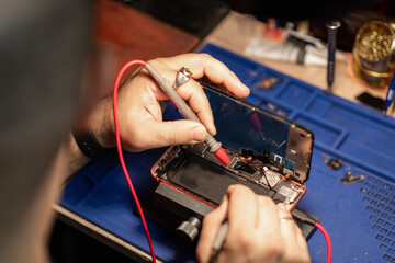 Aufkleber - Technician performing smartphone battery repair on a device at a workshop in the evening