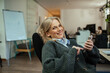 © Marko Geber - Relaxed woman using smartphone in office chair, taking a break from work