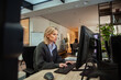 © Marko Geber - Focused woman working at dual monitors in modern office setting
