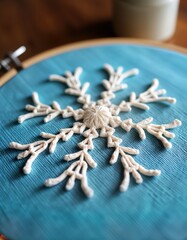 Poster - Embroidered snowflake on blue fabric. Winter holiday gift idea. Handmade home decor. Needlework craft. Cozy warm light. Soft yarn texture. Blue textile background.