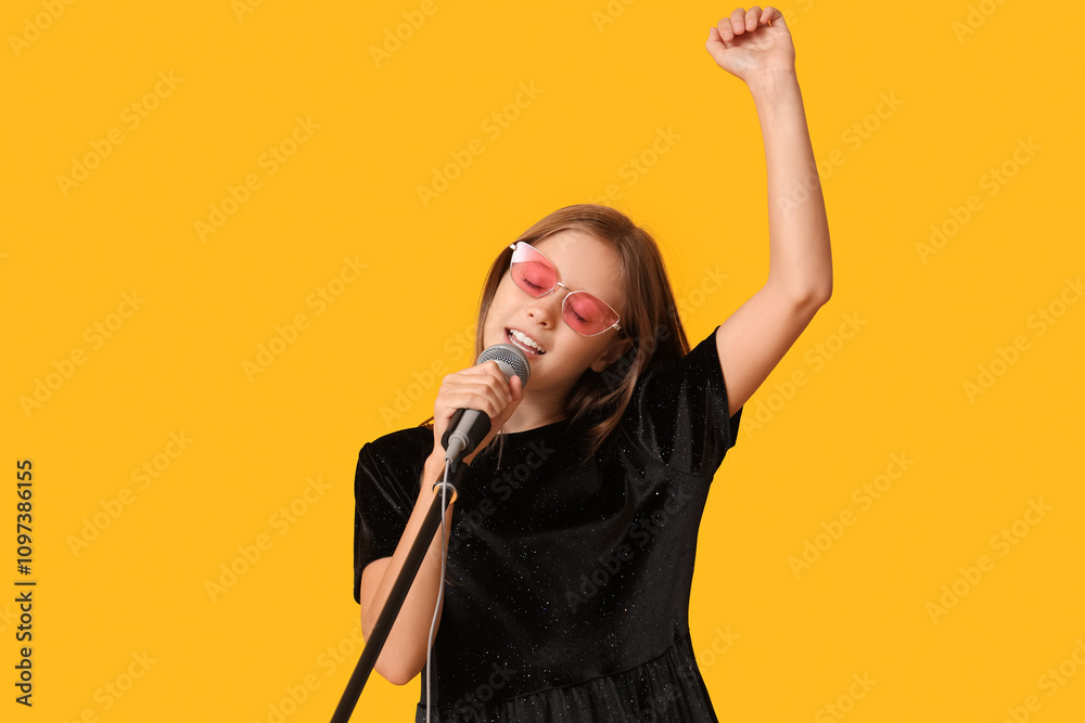 Cute girl singing with modern microphone on yellow background