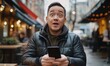 © Slamet - Amazed man looking at phone outdoors.