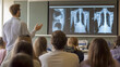 © KeetaKawee - Medical professional delivering a lecture on radiology to a group of attentive students in a modern classroom setting with projected X-ray images.