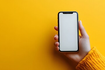 hand holding smartphone with blank screen against vibrant yellow background