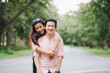 © NanSan - A young couple walks hand in hand, shoulder-hugging romantically in a lush green forest. Smiling happily, they express deep love, trust, and stability, embracing the beauty of nature together