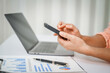 © NanSan - A close-up of a businesswoman working on a laptop in an office. As an accountant, she records financial data, verifies documents, manages income and expenses, ensuring accurate financial reporting
