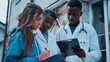 © mahamad - Caucasian professional doctor and African assistant discussing tasks in a hospital, with the young woman and African man looking at information on a clipboard.