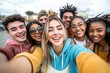 © Kseniya - Multiracial group of happy friends taking selfie in urban setting with diverse college students laughing together outdoors