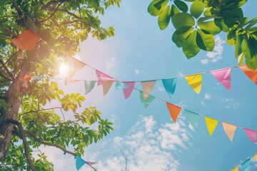 Wall Mural - colorful pennant decoration in tree foliage summer party background.