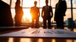 © nattapon98 - business strategy leadership scalability Concept. Silhouetted figures in business attire stand against a sunset backdrop, with a report in focus on the table, symbolizing corporate strategy