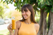 © luismolinero - Young woman holding an orange juice at outdoors with happy expression