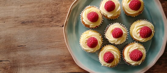 Canvas Print - Delicious cupcakes with white chocolate and raspberries on a ceramic plate shot overhead on a wooden table with space for text