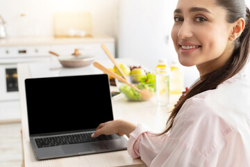 Aufkleber - Portrait of happy smiling young lady using personal computer with black empty screen for mock up design, looking back sitting at dinner table in kitchen, working and typing on keyboard