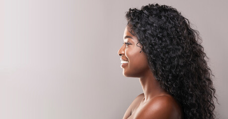 Wall Mural - Profile portrait of beautiful smiling black woman with flawless skin, healthy curly hair, and white teeth. Panorama with free space